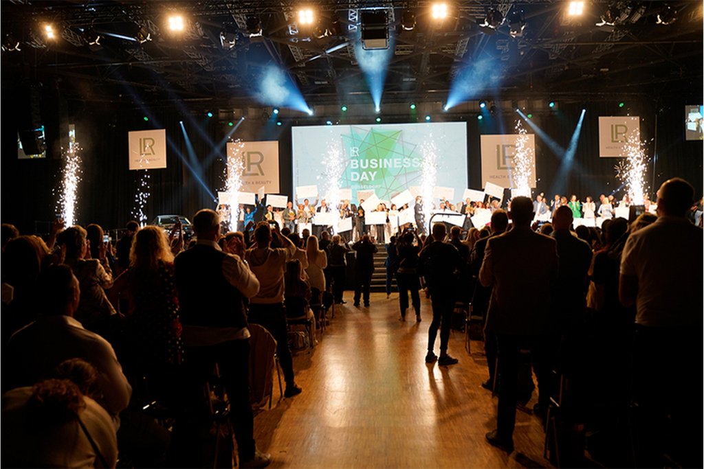 Evento de LR Health & Beauty con iluminación escénica y socios reunidos para una celebración motivadora.