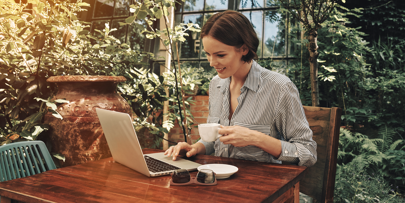 Mujer sonriente leyendo noticias en una tablet al aire libre.