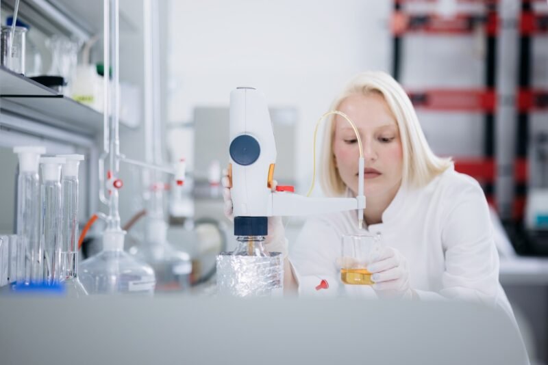 Technicienne LR Health & Beauty en laboratoire effectuant un test de qualité sur un échantillon liquide.