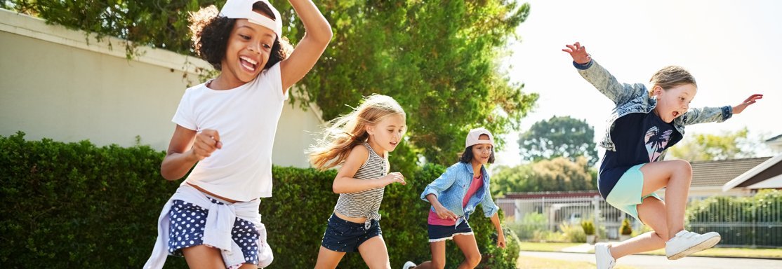 Grupo de niños corriendo y saltando al aire libre, llenos de alegría y energía.