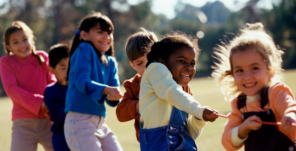 Niños de diferentes orígenes jugando al aire libre con alegría y complicidad.