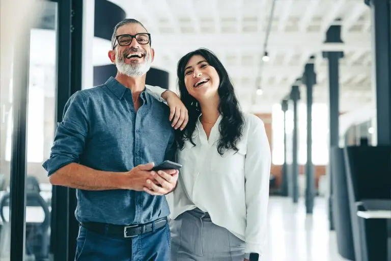 Deux collègues souriants dans un espace de travail moderne, incarnant la convivialité et la durabilité en entreprise.